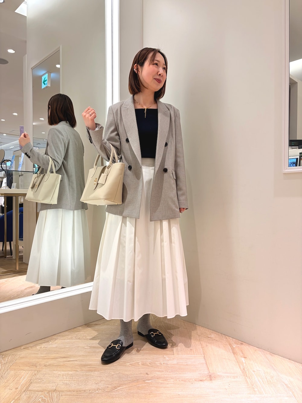 ホワイト系のスカート、ベージュ系のテーラードジャケット、ベージュ系のトートバッグを着用したレディースの春コーディネートの5枚目の写真