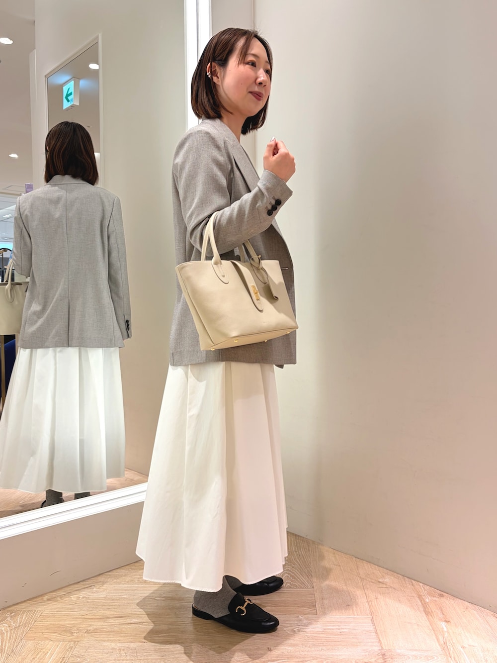 ホワイト系のスカート、ベージュ系のテーラードジャケット、ベージュ系のトートバッグを着用したレディースの春コーディネートの3枚目の写真