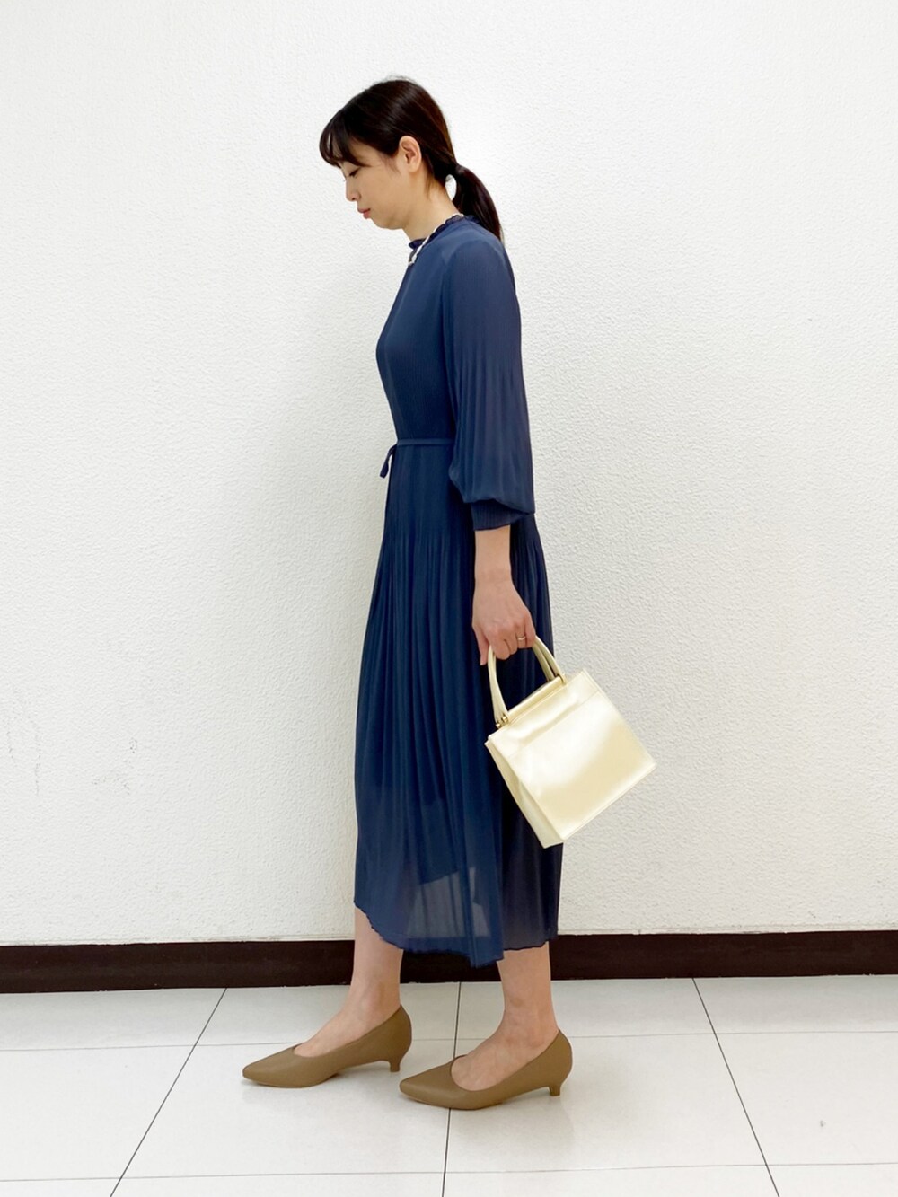 ホワイト系のハンドバッグ、ブルー系のワンピース、ベージュ系のトレンチコートを着用したレディースの冬コーディネートの4枚目の写真