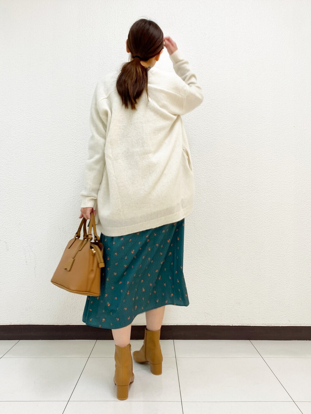 グリーン系のワンピース、ホワイト系のカーディガン/ボレロ、イエロー系のブーツを着用したレディースの秋コーディネートの3枚目の写真