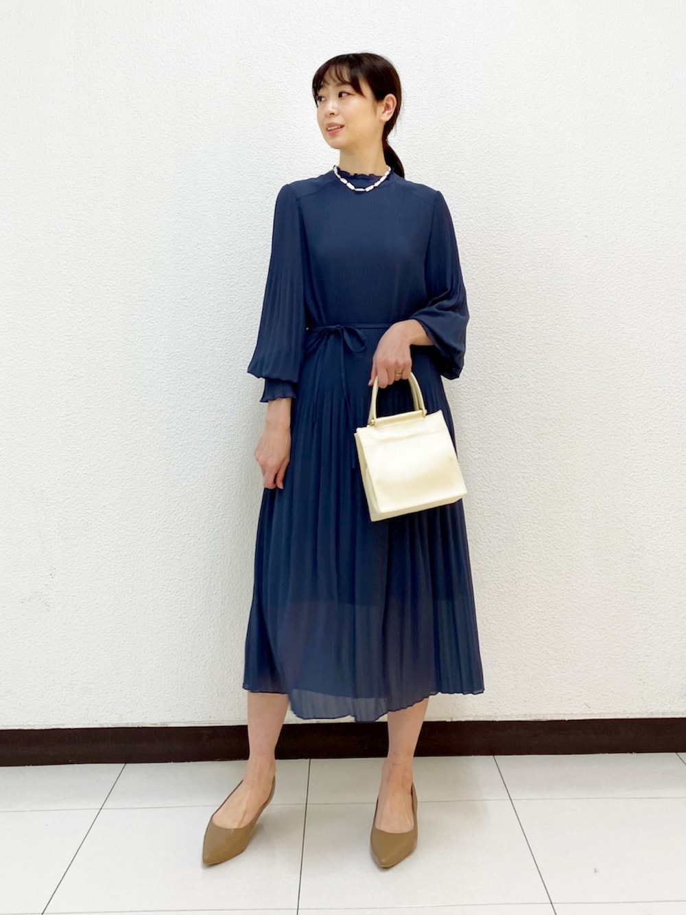 ホワイト系のハンドバッグ、ブルー系のワンピース、ベージュ系のトレンチコートを着用したレディースの冬コーディネートの5枚目の写真