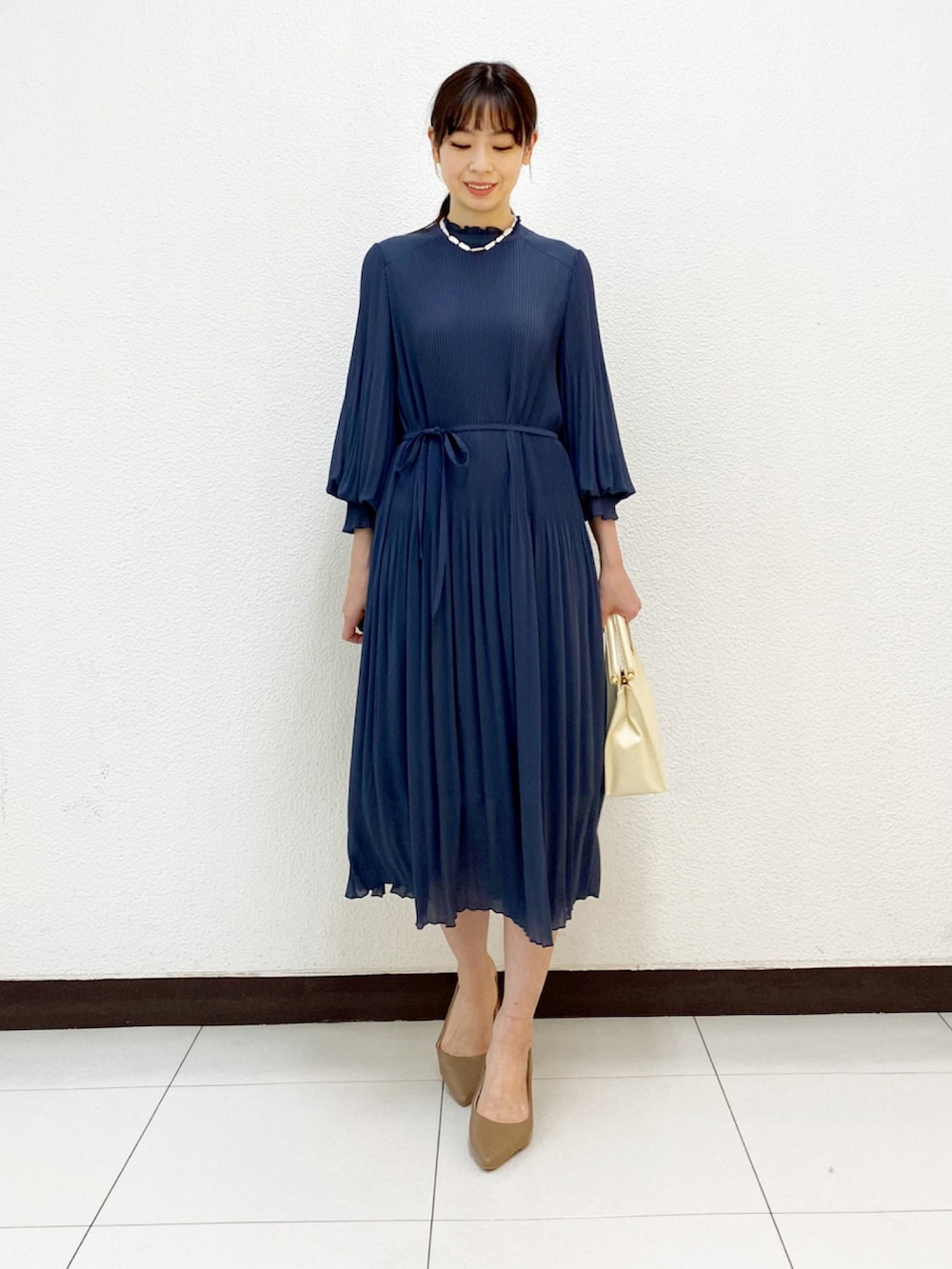 ホワイト系のハンドバッグ、ブルー系のワンピース、ベージュ系のトレンチコートを着用したレディースの冬コーディネートの3枚目の写真