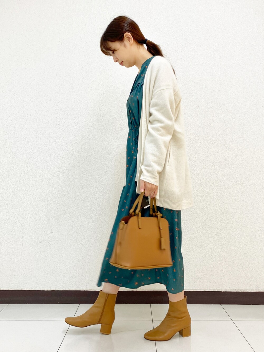 グリーン系のワンピース、ホワイト系のカーディガン/ボレロ、イエロー系のブーツを着用したレディースの秋コーディネートの2枚目の写真