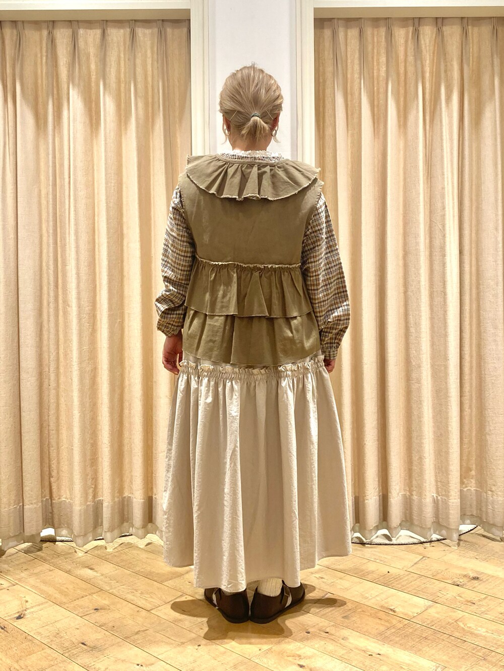 ホワイト系のシャツ/ブラウス、グリーン系のベスト、ベージュ系のスカートを着用したレディースの秋コーディネートの4枚目の写真