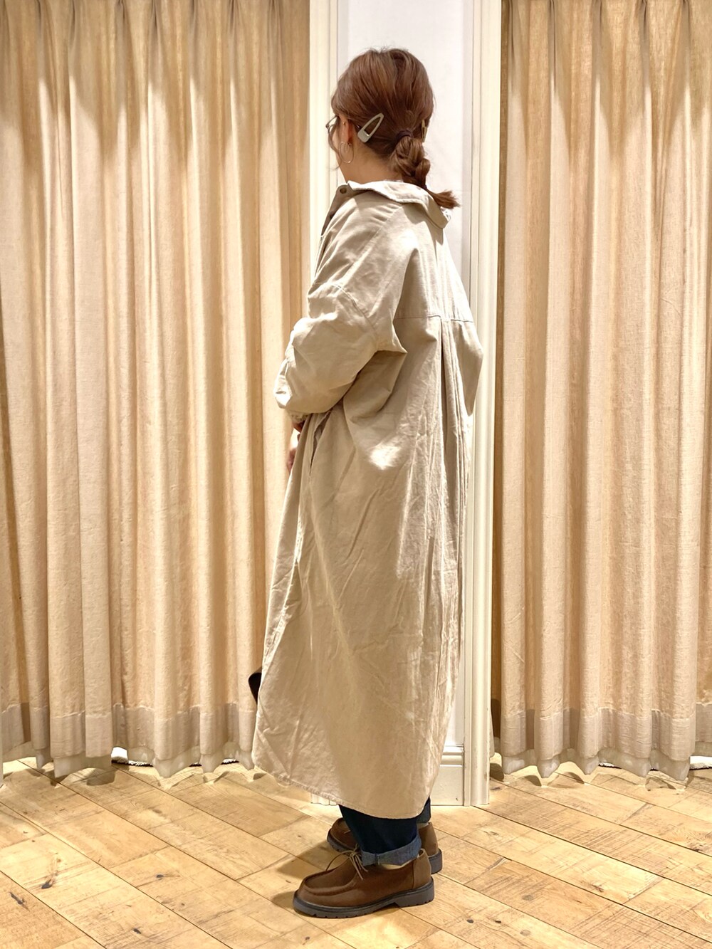 ベージュ系のワンピース、ホワイト系のニット/セーター、ブルー系のデニムパンツを着用したレディースの秋コーディネートの2枚目の写真