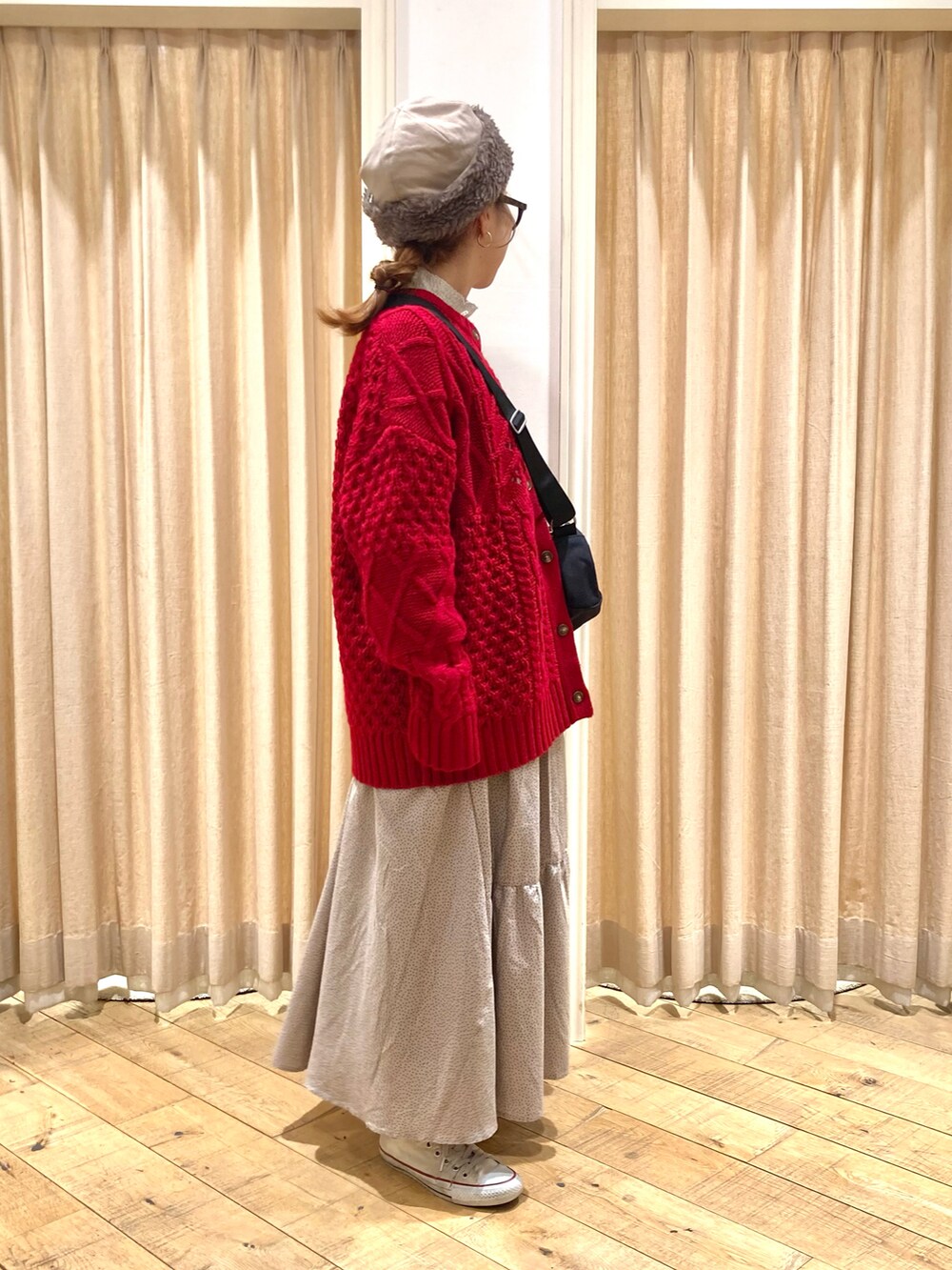 レッド系のカーディガン/ボレロ、ベージュ系のスカート、ブラック系のハンドバッグを着用したレディースの冬コーディネートの5枚目の写真