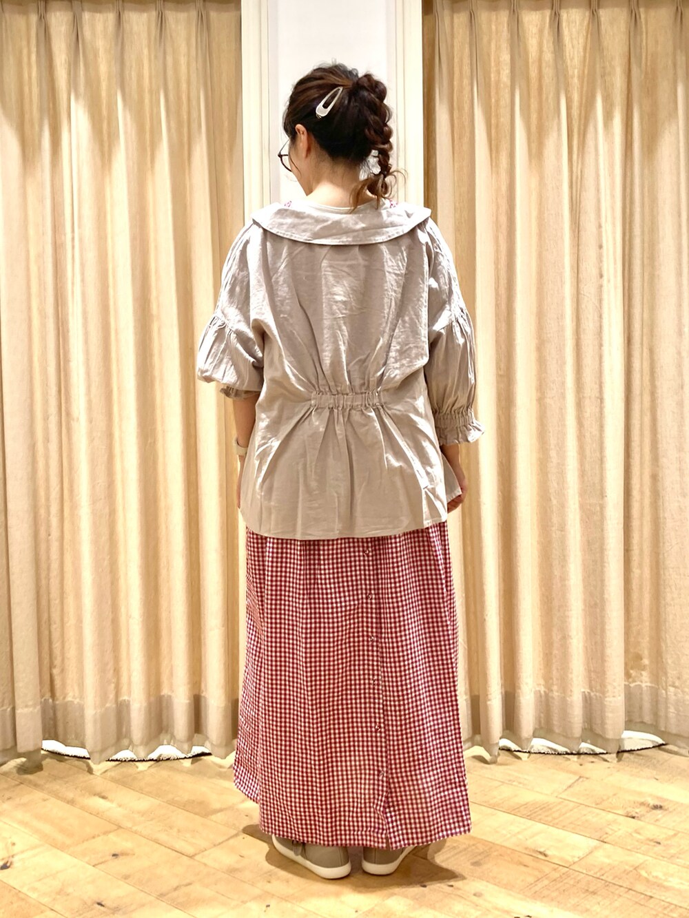 レッド系のワンピース、ベージュ系のシャツ/ブラウス、ブラウン系のスニーカーを着用したレディースの秋コーディネートの2枚目の写真