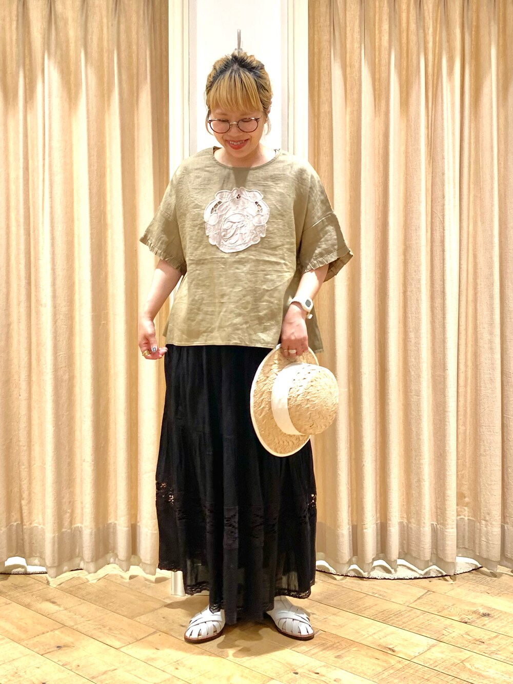 イエロー系のシャツ/ブラウス、ブラック系のスカート、ホワイト系のサンダルを着用したレディースの夏コーディネートの2枚目の写真