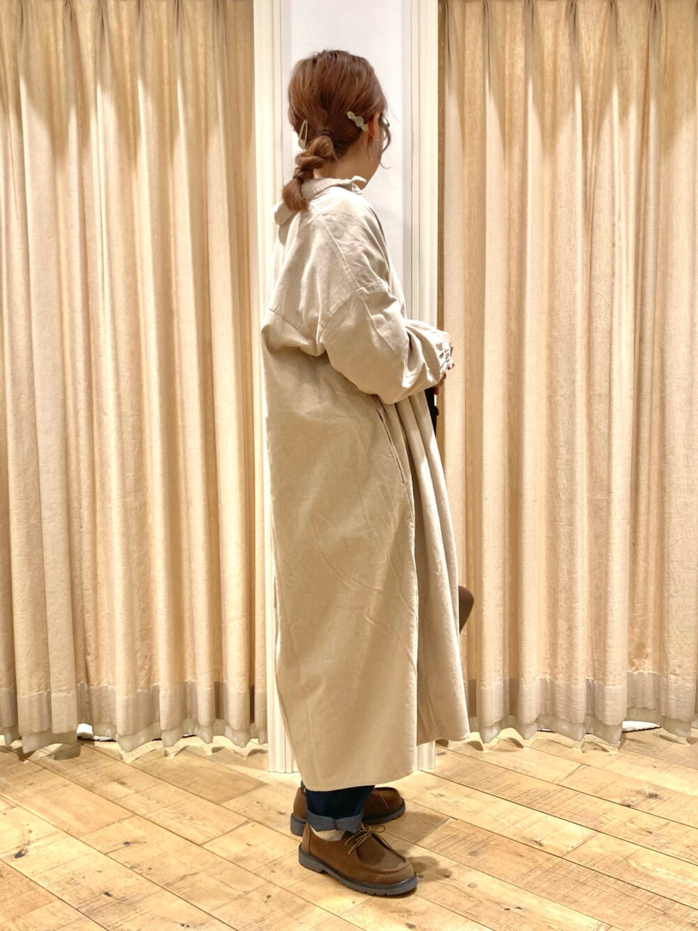 ベージュ系のワンピース、ホワイト系のニット/セーター、ブルー系のデニムパンツを着用したレディースの秋コーディネートの4枚目の写真