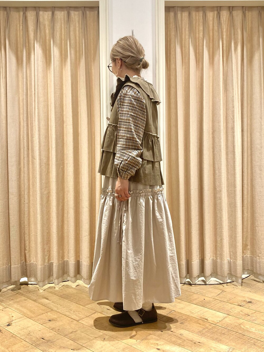 ホワイト系のシャツ/ブラウス、グリーン系のベスト、ベージュ系のスカートを着用したレディースの秋コーディネートの3枚目の写真