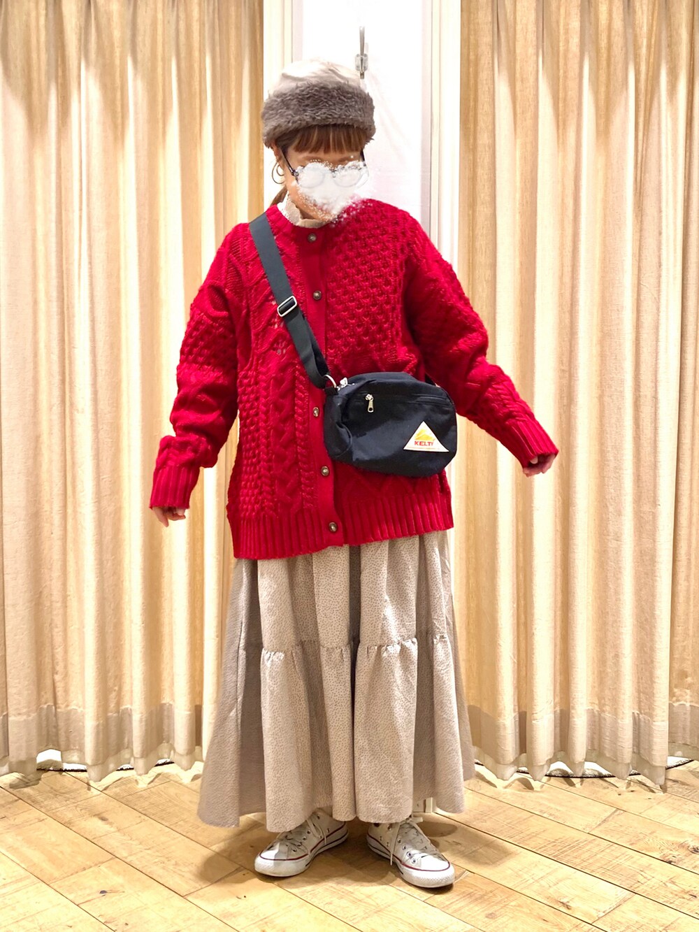 レッド系のカーディガン/ボレロ、ベージュ系のスカート、ブラック系のハンドバッグを着用したレディースの冬コーディネートの2枚目の写真