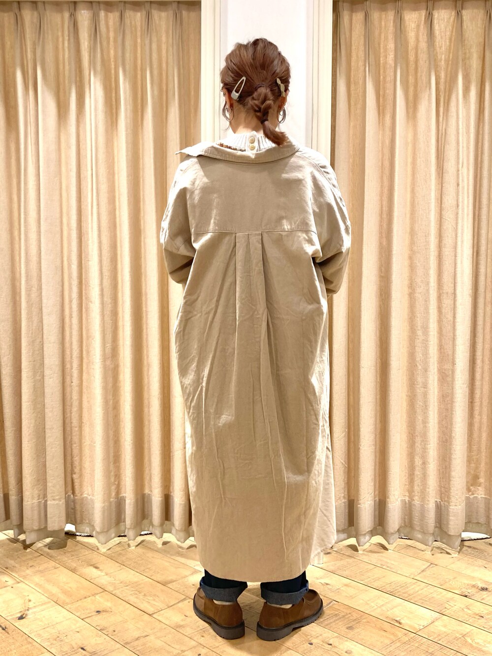 ベージュ系のワンピース、ホワイト系のニット/セーター、ブルー系のデニムパンツを着用したレディースの秋コーディネートの3枚目の写真