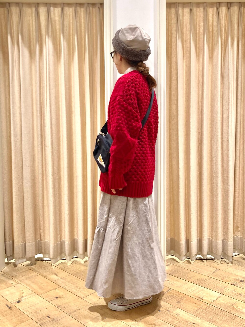 レッド系のカーディガン/ボレロ、ベージュ系のスカート、ブラック系のハンドバッグを着用したレディースの冬コーディネートの3枚目の写真