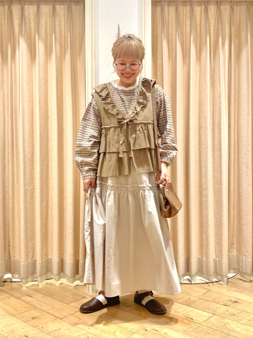 ホワイト系のシャツ/ブラウス、グリーン系のベスト、ベージュ系のスカートを着用したレディースの秋コーディネートの2枚目の写真