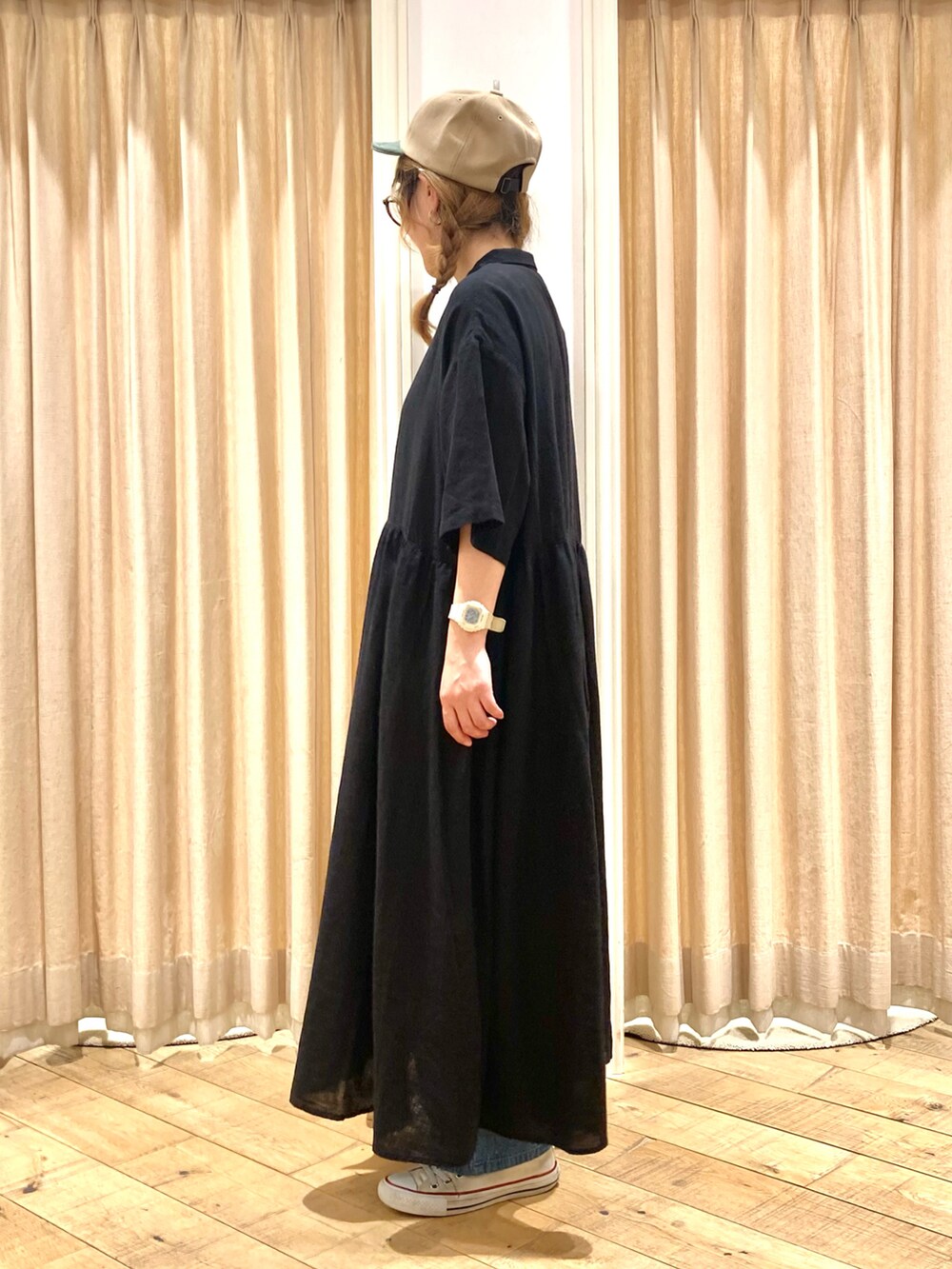 ブラック系のワンピース、ブルー系のデニムパンツ、ベージュ系のハンドバッグを着用したレディースの春コーディネートの2枚目の写真