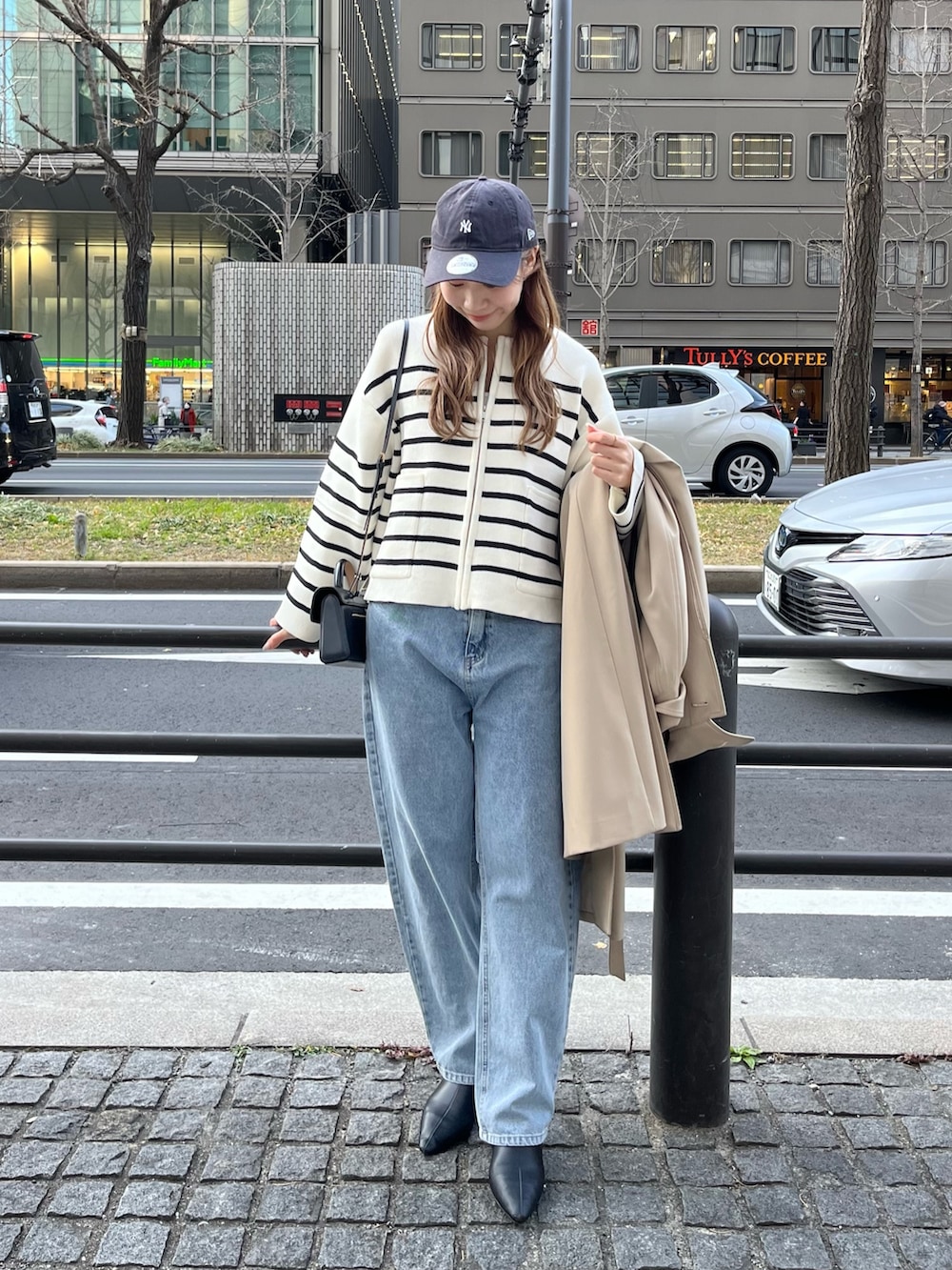 ベージュ系のステンカラーコート、ホワイト系のカーディガン/ボレロ、ブルー系のデニムパンツを着用したレディースの冬コーディネートの3枚目の写真