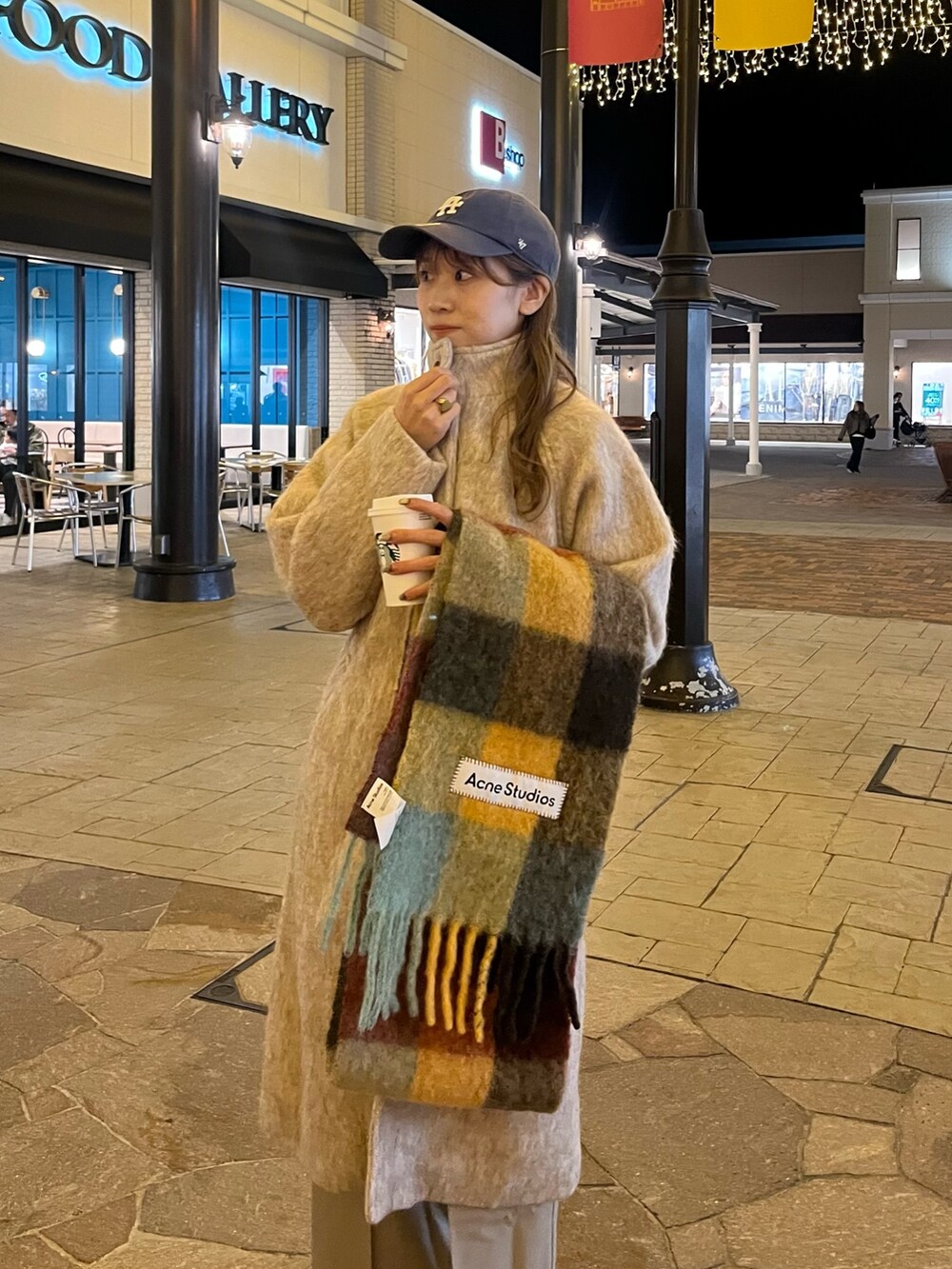 ベージュ系のステンカラーコート、ベージュ系のスラックス、ブラック系のブーツを着用したレディースの秋コーディネートの3枚目の写真