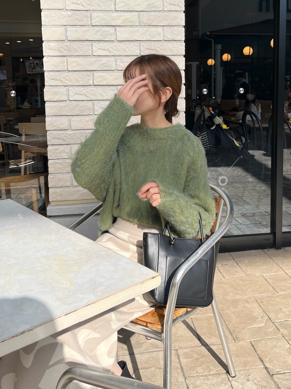 グリーン系のニット/セーター、ベージュ系のスカート、ブラック系のブーツを着用したレディースの冬コーディネートの4枚目の写真