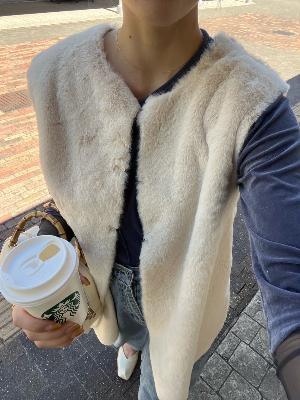 ホワイト系のベスト、ブルー系のTシャツ/カットソー、ブルー系のデニムパンツを着用したレディースの秋コーディネートの7枚目の写真