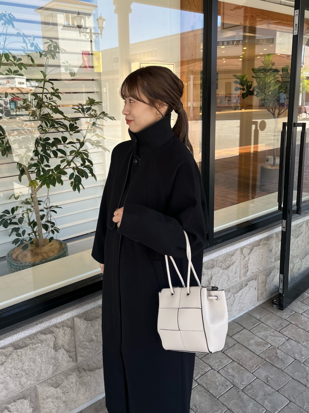 ホワイト系のニット/セーター、ブルー系のデニムパンツ、ホワイト系のショルダーバッグを着用したレディースの秋コーディネートの2枚目の写真