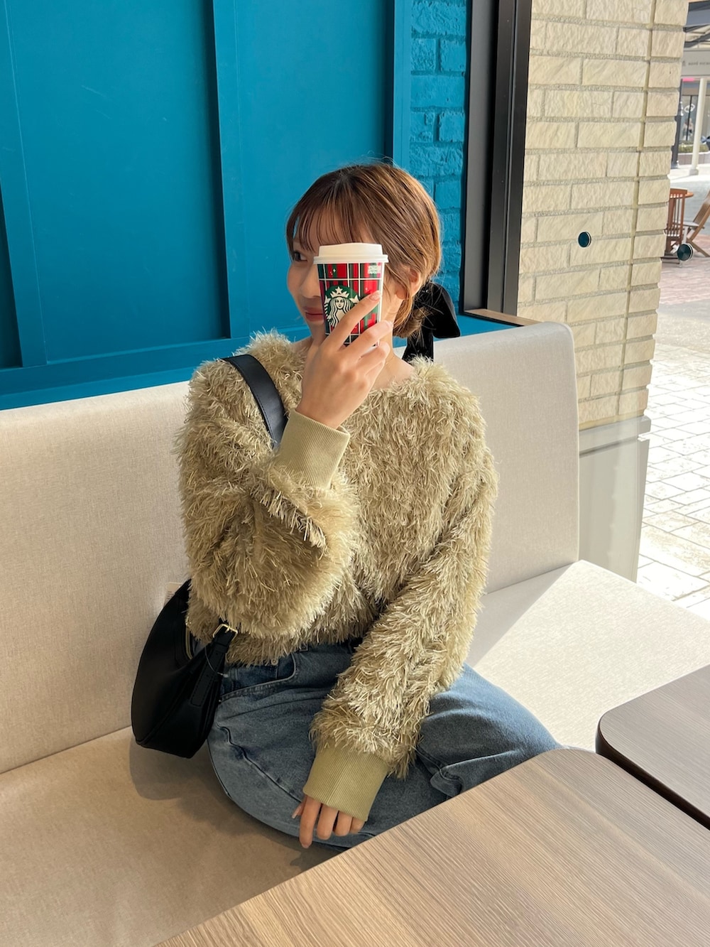 グリーン系のTシャツ/カットソー、ブルー系のデニムパンツ、ブラック系のブーツを着用したレディースの冬コーディネートの4枚目の写真