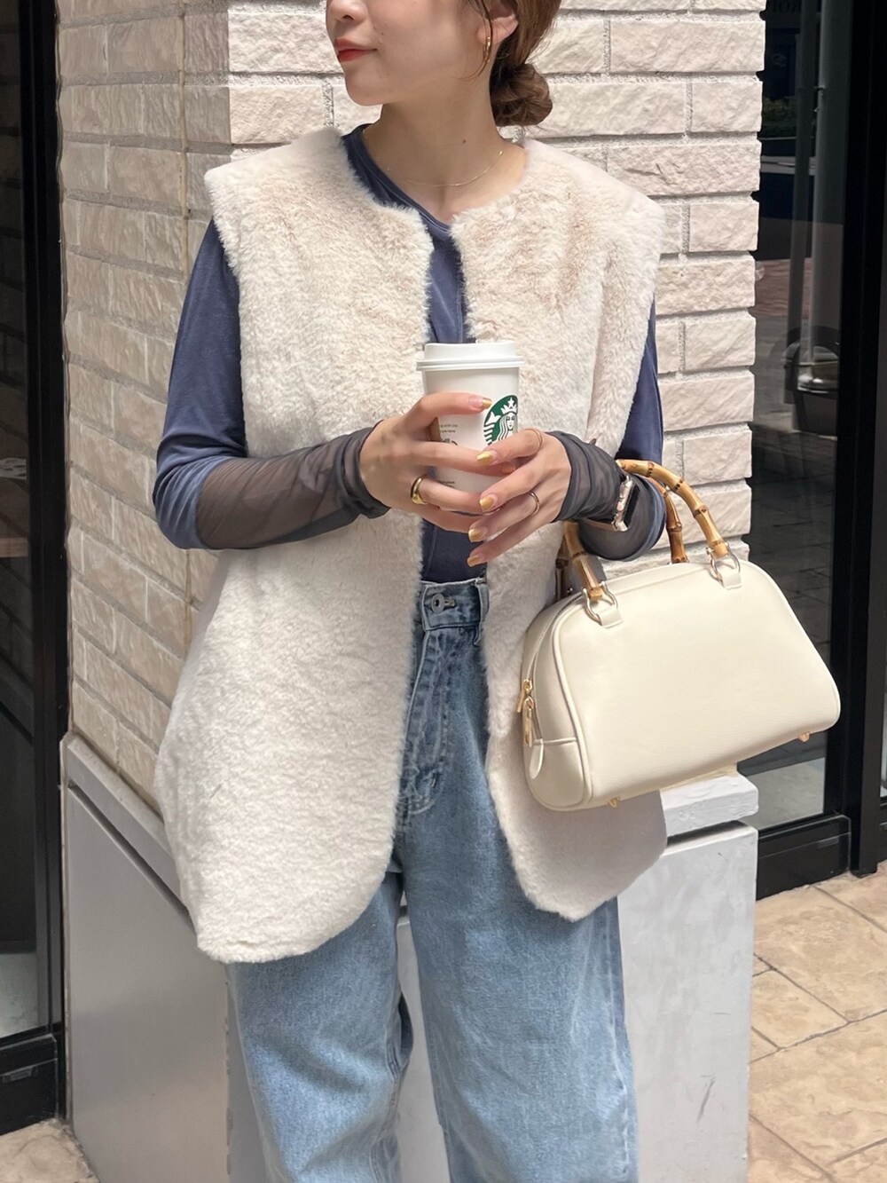 ホワイト系のベスト、ブルー系のTシャツ/カットソー、ブルー系のデニムパンツを着用したレディースの秋コーディネートの5枚目の写真