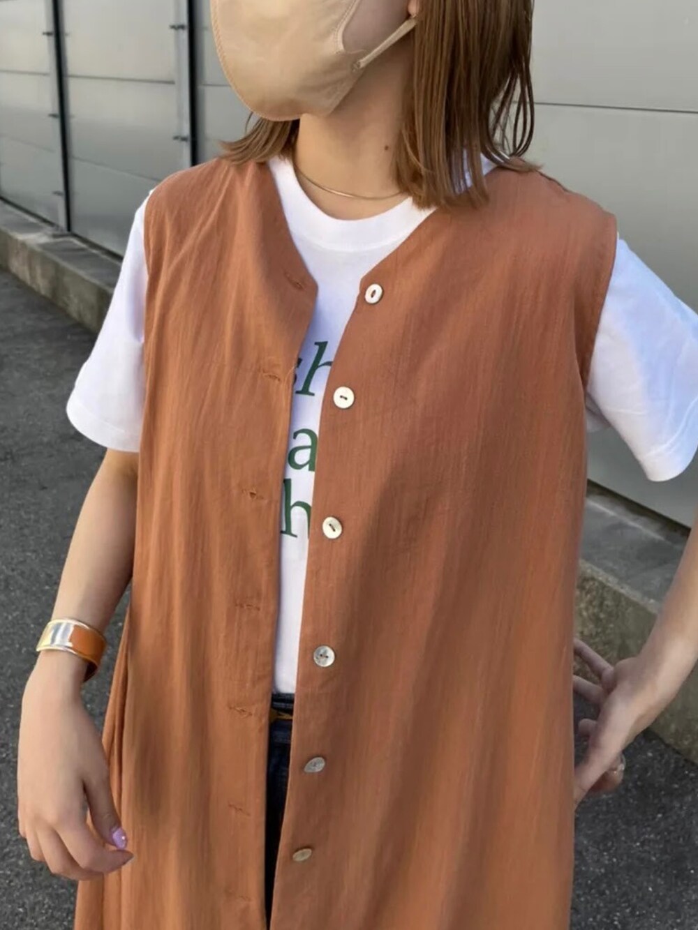 オレンジ系のワンピース、ブルー系のデニムパンツを着用したレディースの夏コーディネートの2枚目の写真