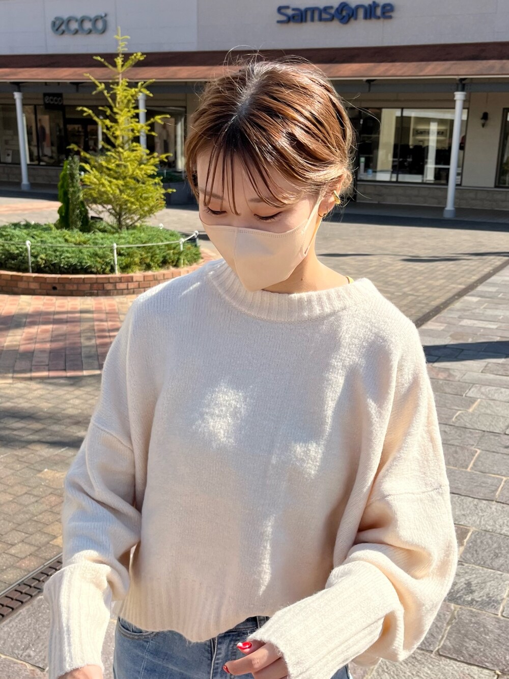 ホワイト系のニット/セーター、ブルー系のデニムパンツ、レッド系のショルダーバッグを着用したレディースの秋コーディネートの2枚目の写真