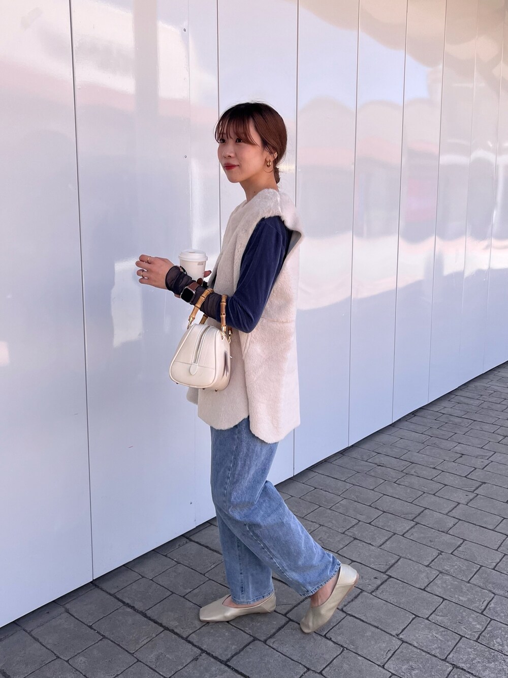 ホワイト系のベスト、ブルー系のTシャツ/カットソー、ブルー系のデニムパンツを着用したレディースの秋コーディネートの3枚目の写真