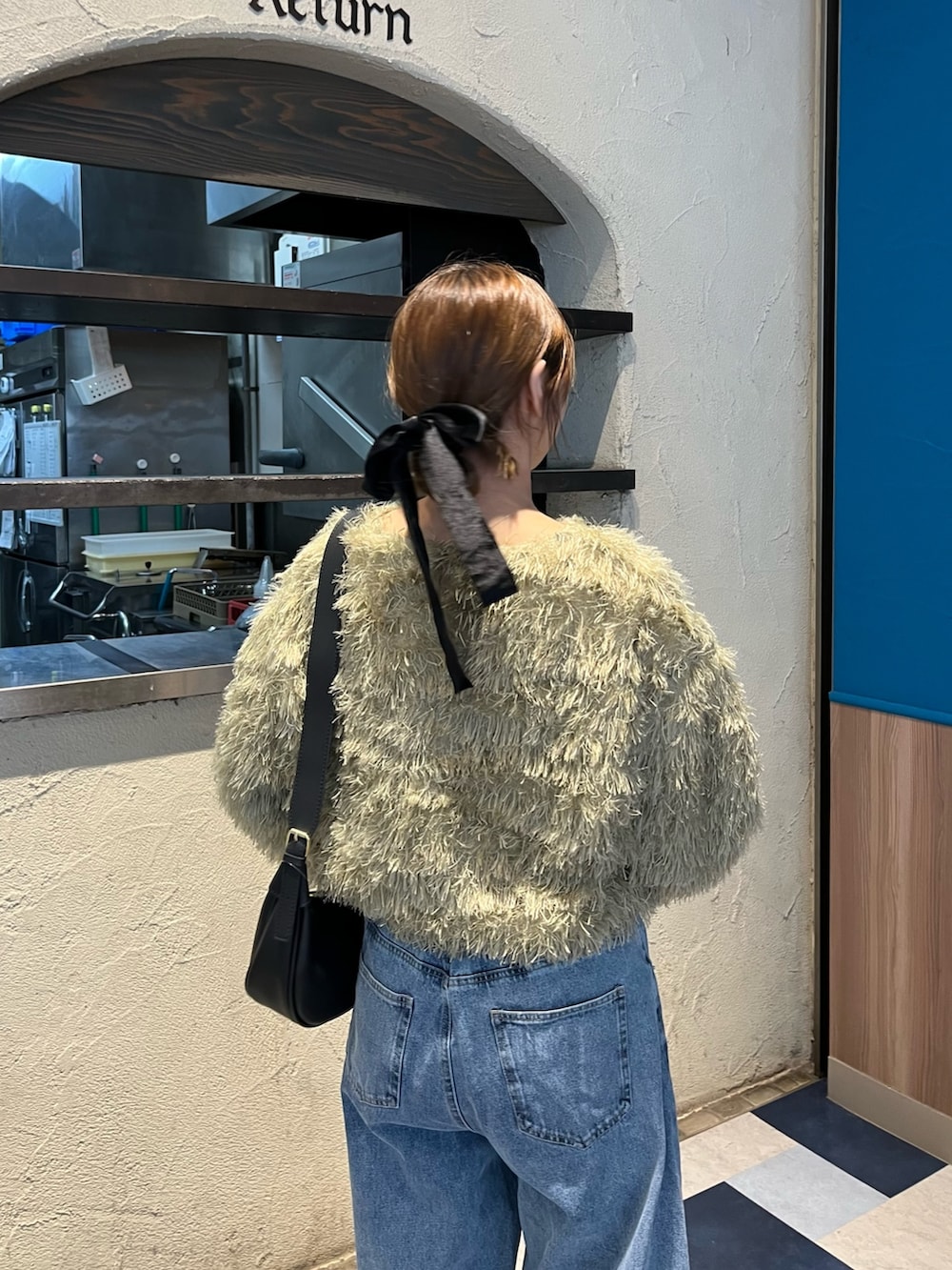 グリーン系のTシャツ/カットソー、ブルー系のデニムパンツ、ブラック系のブーツを着用したレディースの冬コーディネートの5枚目の写真