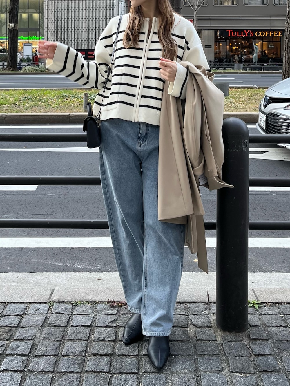 ベージュ系のステンカラーコート、ホワイト系のカーディガン/ボレロ、ブルー系のデニムパンツを着用したレディースの冬コーディネートの5枚目の写真