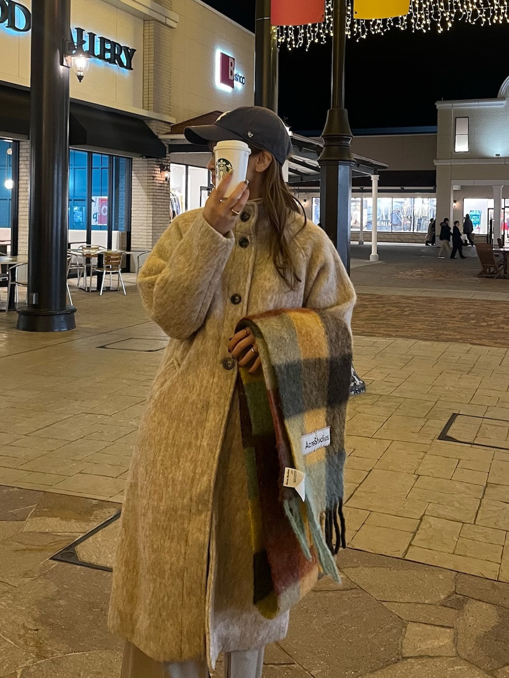 ベージュ系のステンカラーコート、ベージュ系のスラックス、ブラック系のブーツを着用したレディースの秋コーディネートの5枚目の写真