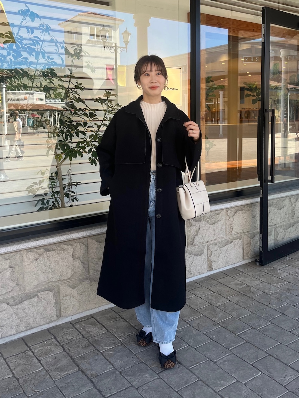 ホワイト系のニット/セーター、ブルー系のデニムパンツ、ホワイト系のショルダーバッグを着用したレディースの秋コーディネートの5枚目の写真