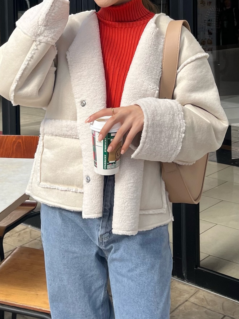 オレンジ系のニット/セーター、ホワイト系のブルゾン、ベージュ系のショルダーバッグを着用したレディースの秋コーディネートの5枚目の写真