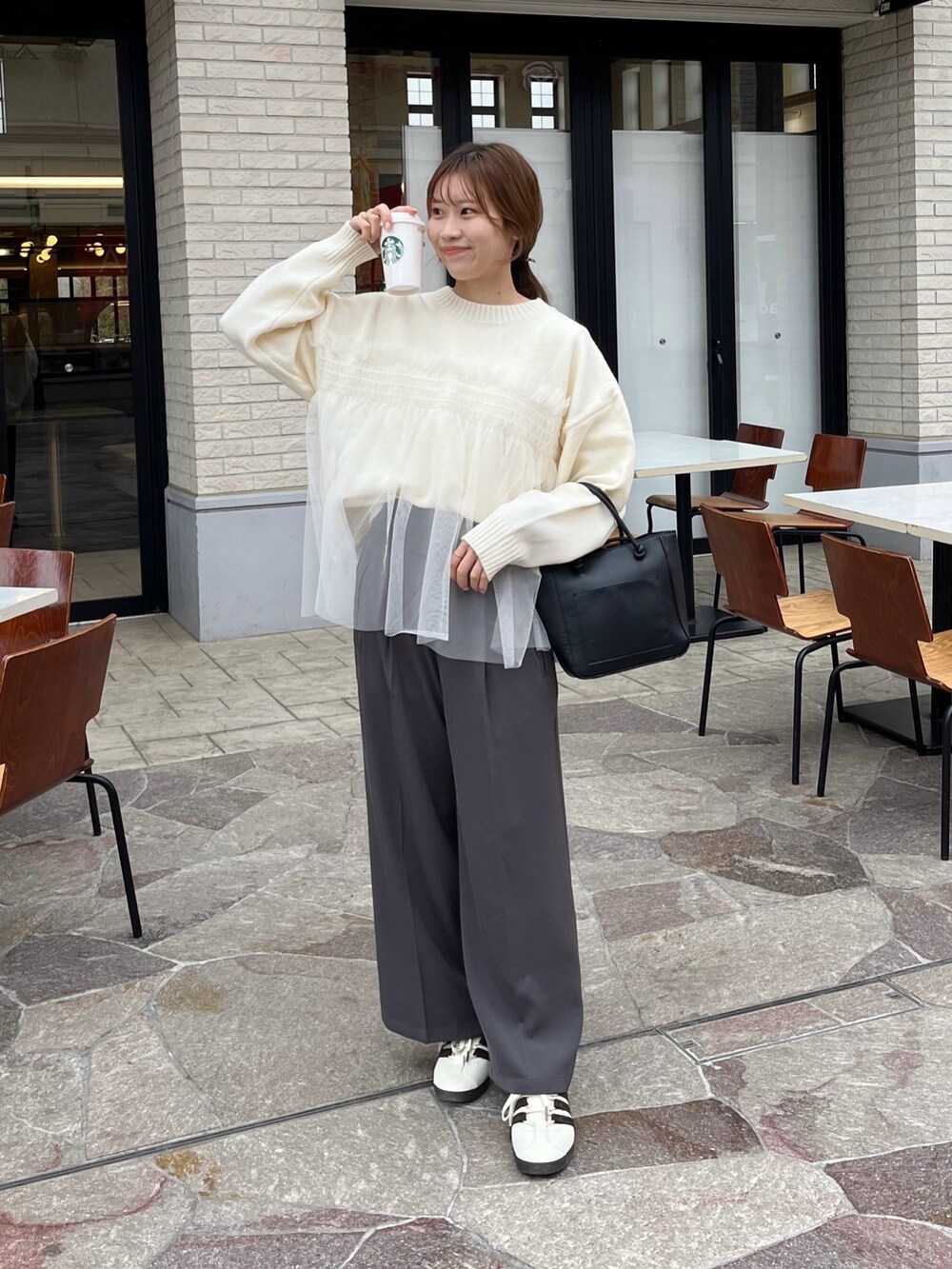 ホワイト系のニット/セーター、グレー系のスラックスを着用したレディースの冬コーディネートの2枚目の写真