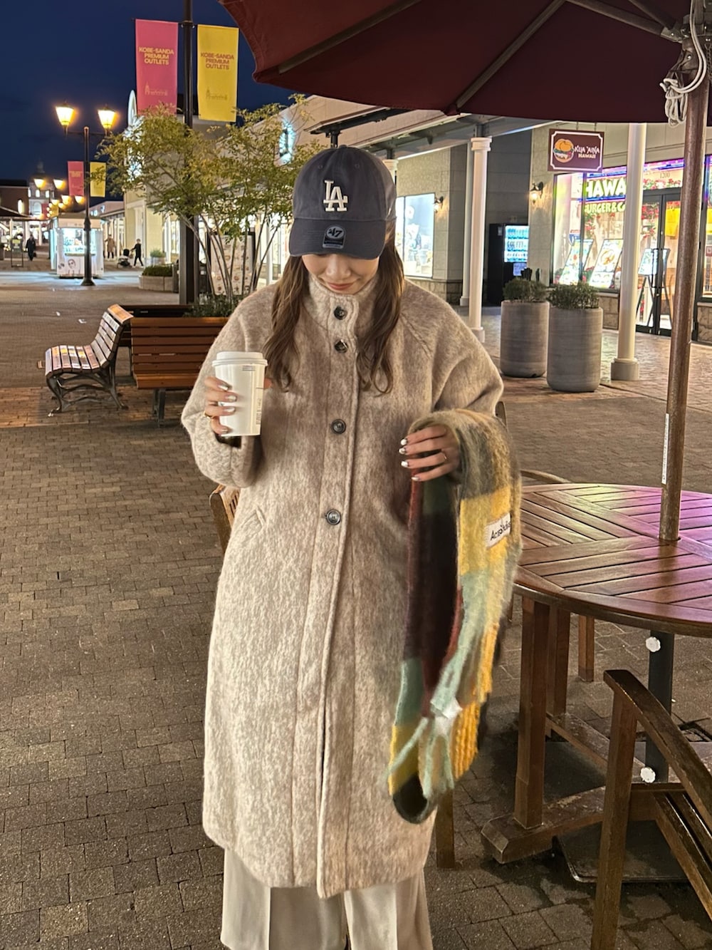 ベージュ系のステンカラーコート、ベージュ系のスラックス、ブラック系のブーツを着用したレディースの秋コーディネートの2枚目の写真