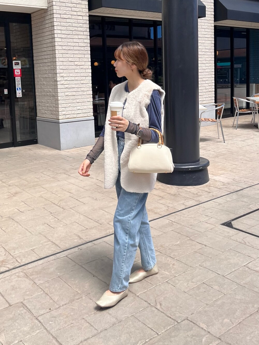 ホワイト系のベスト、ブルー系のTシャツ/カットソー、ブルー系のデニムパンツを着用したレディースの秋コーディネートの4枚目の写真