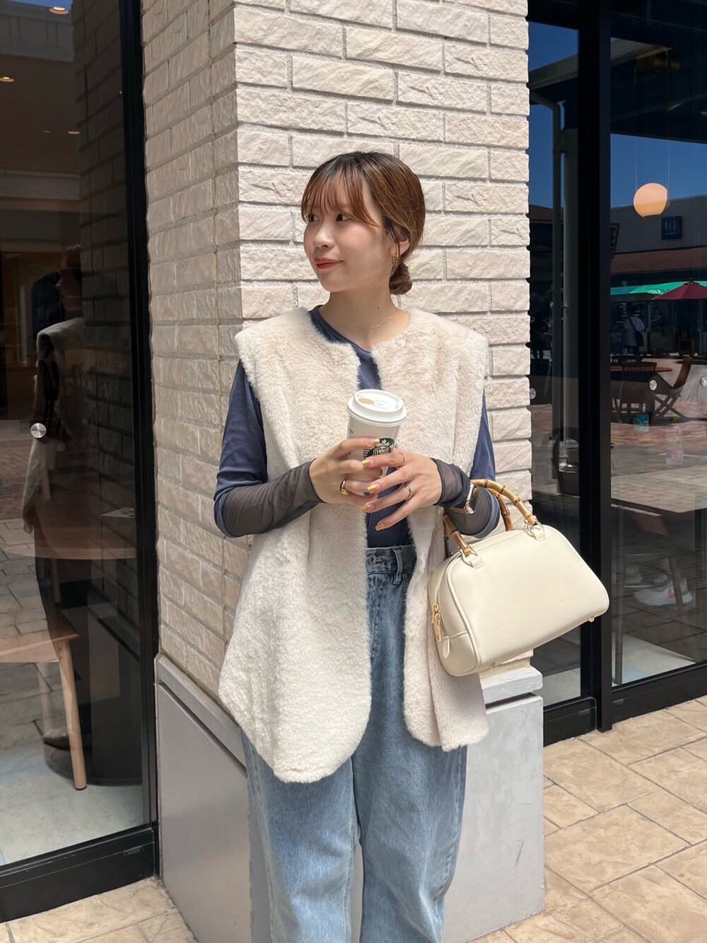 ホワイト系のベスト、ブルー系のTシャツ/カットソー、ブルー系のデニムパンツを着用したレディースの秋コーディネートの6枚目の写真