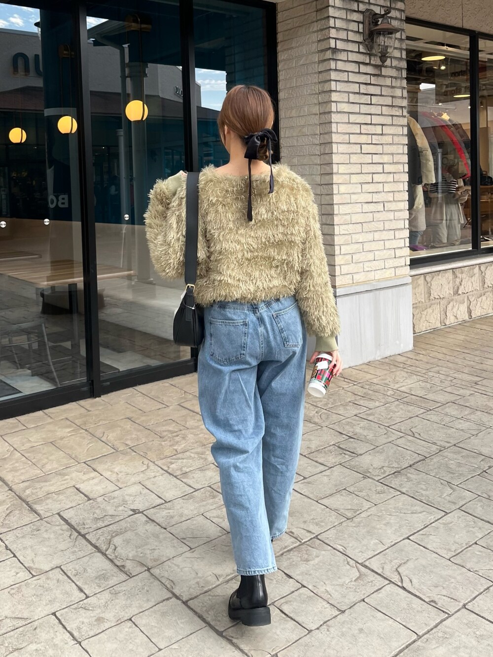 グリーン系のTシャツ/カットソー、ブルー系のデニムパンツ、ブラック系のブーツを着用したレディースの冬コーディネートの2枚目の写真