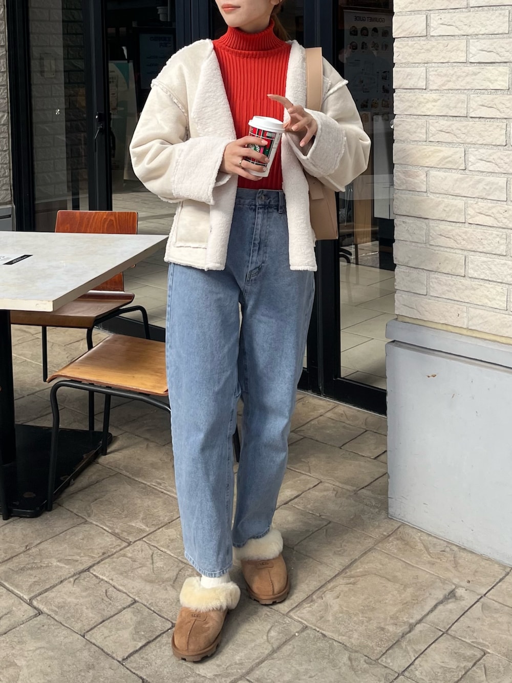 オレンジ系のニット/セーター、ホワイト系のブルゾン、ベージュ系のショルダーバッグを着用したレディースの秋コーディネートの3枚目の写真