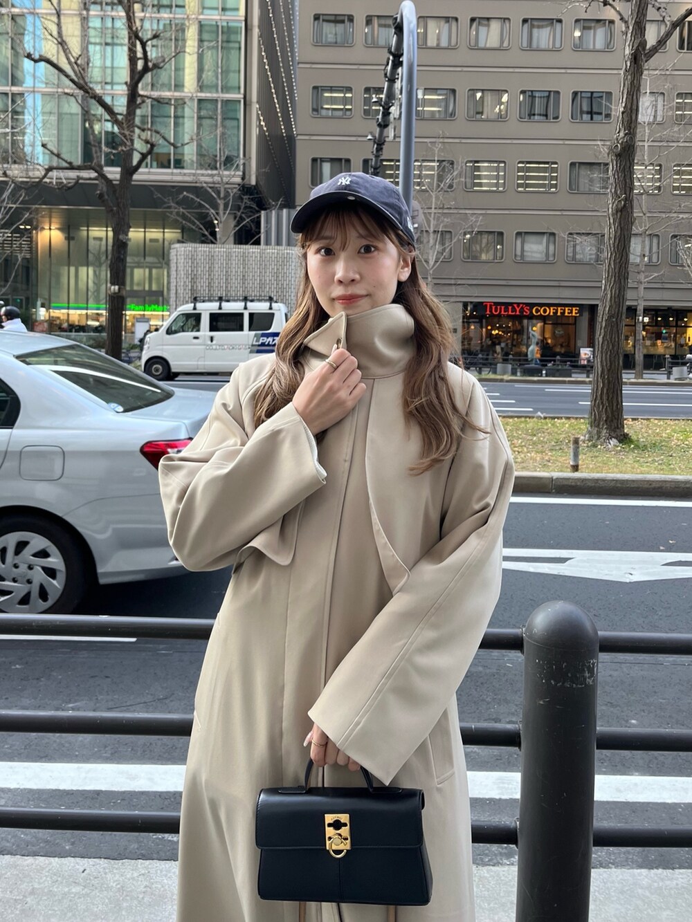 ベージュ系のステンカラーコート、ホワイト系のカーディガン/ボレロ、ブルー系のデニムパンツを着用したレディースの冬コーディネートの4枚目の写真