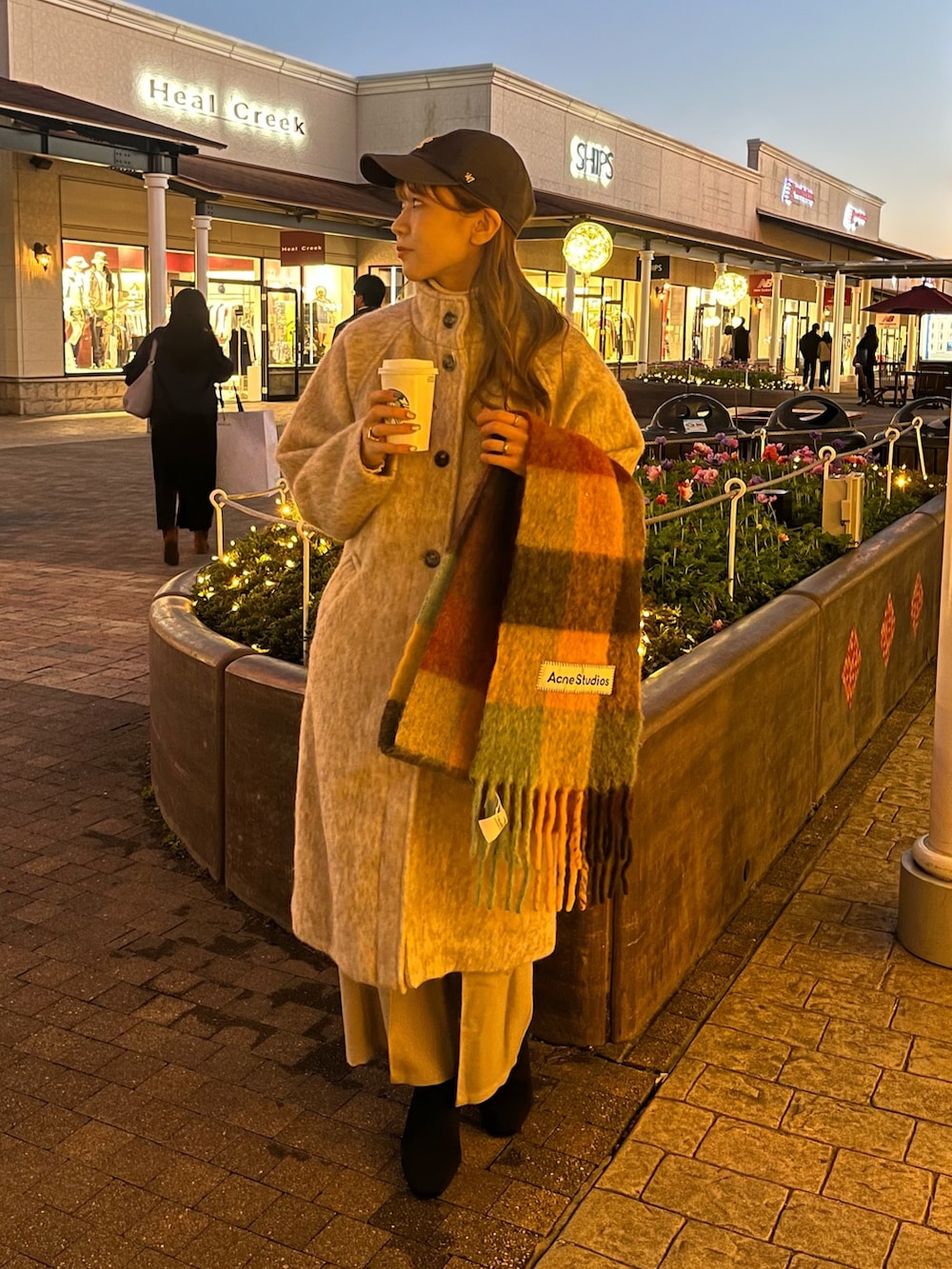 ベージュ系のステンカラーコート、ベージュ系のスラックス、ブラック系のブーツを着用したレディースの秋コーディネートの4枚目の写真