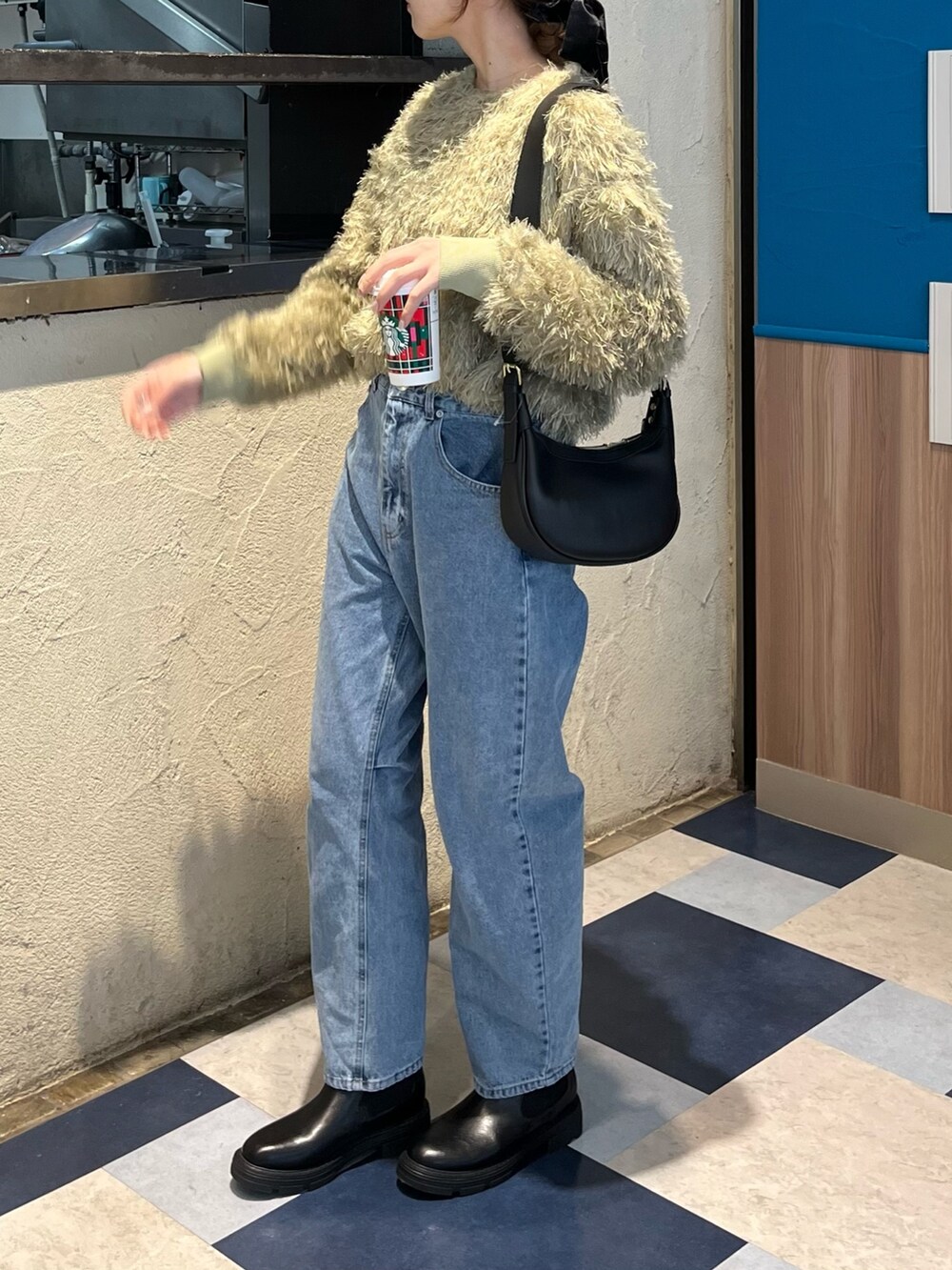 グリーン系のTシャツ/カットソー、ブルー系のデニムパンツ、ブラック系のブーツを着用したレディースの冬コーディネートの6枚目の写真