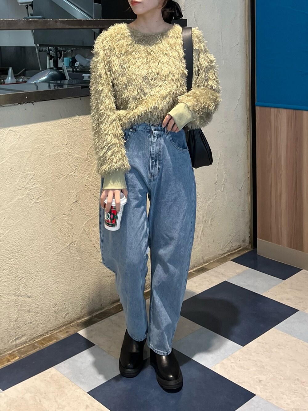 グリーン系のTシャツ/カットソー、ブルー系のデニムパンツ、ブラック系のブーツを着用したレディースの冬コーディネートの7枚目の写真