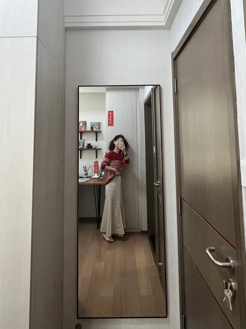 レッド系のニット/セーター、ベージュ系のスカートを着用したレディースの春コーディネートの2枚目の写真