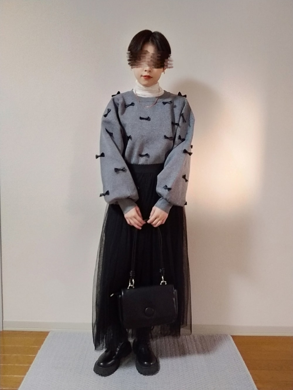 ホワイト系のTシャツ/カットソー、グレー系のニット/セーター、ブラック系のスカートを着用したレディースの秋コーディネートの2枚目の写真