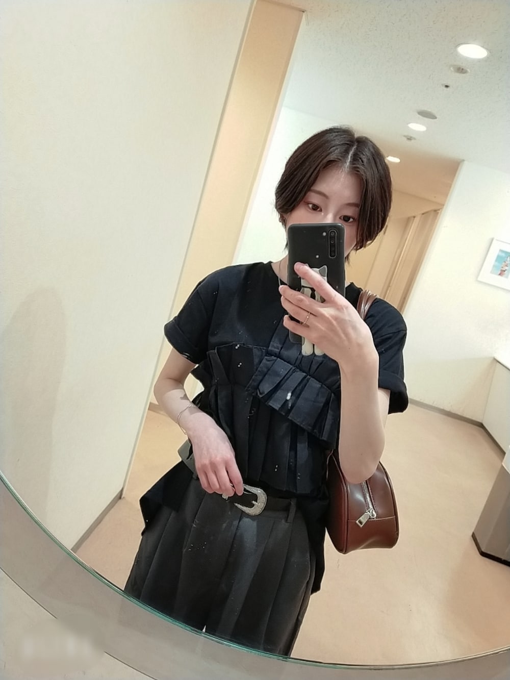 ブラック系のTシャツ/カットソー、ブラウン系のボストンバッグ、グレー系のスラックスを着用したレディースの秋コーディネートの2枚目の写真