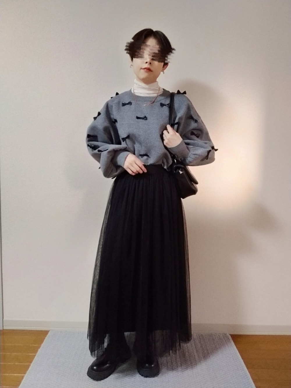 ホワイト系のTシャツ/カットソー、グレー系のニット/セーター、ブラック系のスカートを着用したレディースの秋コーディネートの3枚目の写真