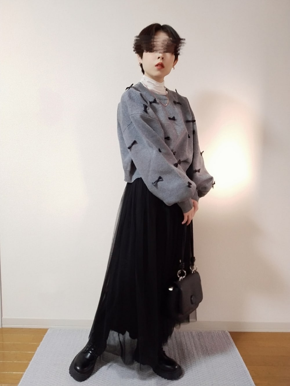 ホワイト系のTシャツ/カットソー、グレー系のニット/セーター、ブラック系のスカートを着用したレディースの秋コーディネートの4枚目の写真