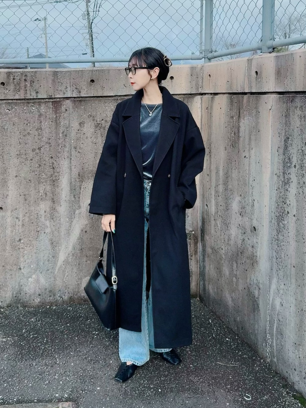 ブルー系のデニムパンツ、グレー系のTシャツ/カットソー、ブラック系のチェスターコートを着用したレディースの冬コーディネートの2枚目の写真